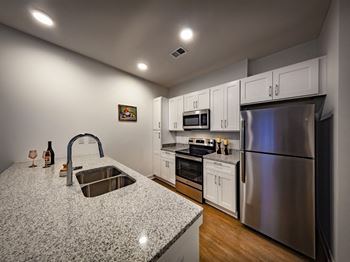 The kitchen features granite counters, wood-look flooring and stainless steel appliances.